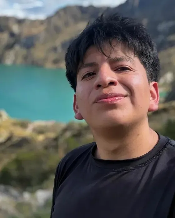 Andrés Collaguazo standing above a turquoise crater lagoon in the Andes