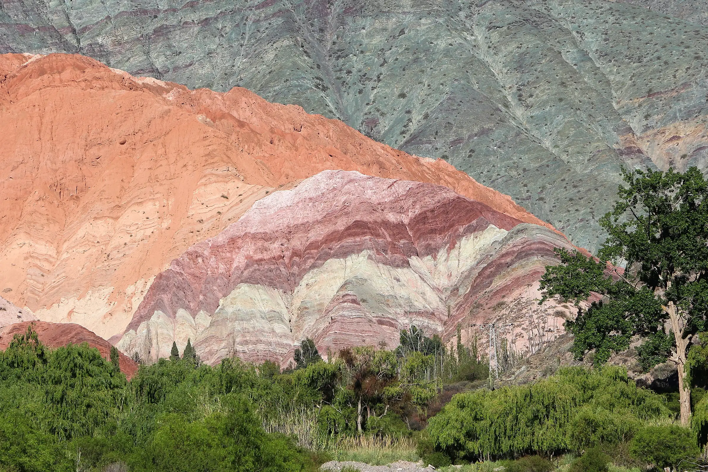 The striped red, pink and green slopes of the Hill of Seven Colors above the village of Purmamarca in Jujuy, Argentina