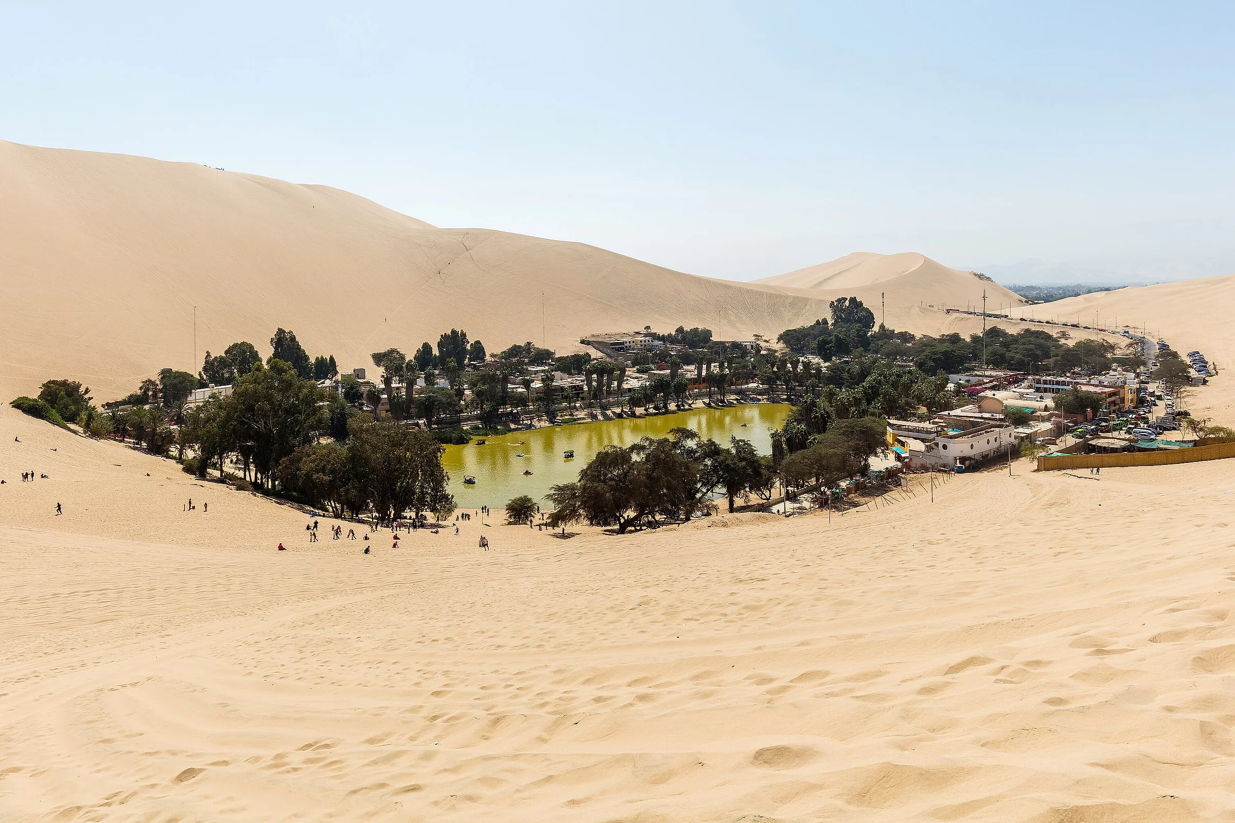 The oasis of Huacachina, its lagoon and palm trees in a hollow of the sand dunes near Ica