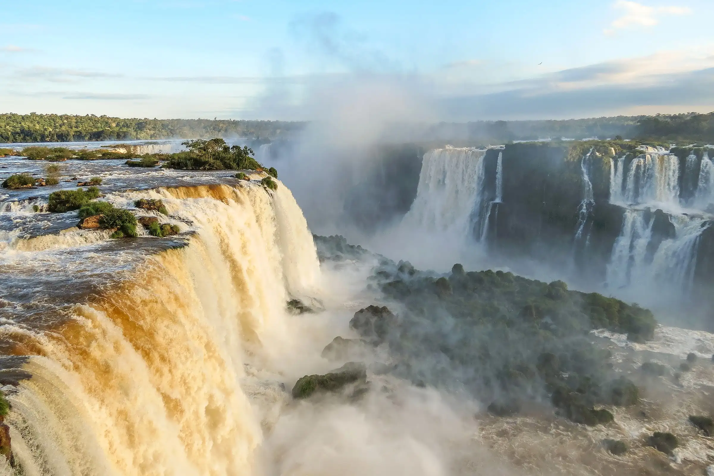 The Iguazu falls seen from above with spray rising between the forested islands