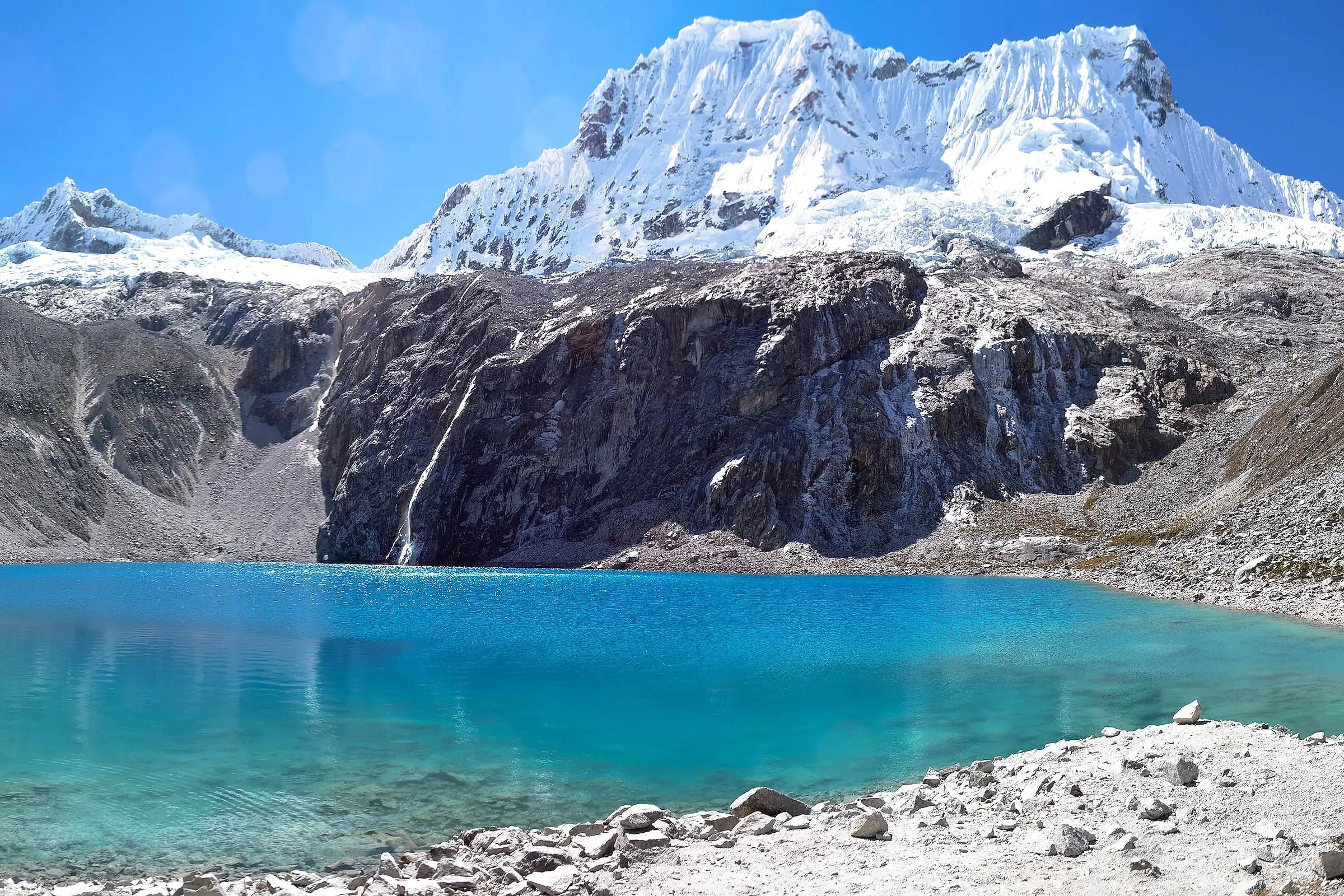 The turquoise water of Laguna 69 below a snow-covered peak of the Cordillera Blanca near Huaraz