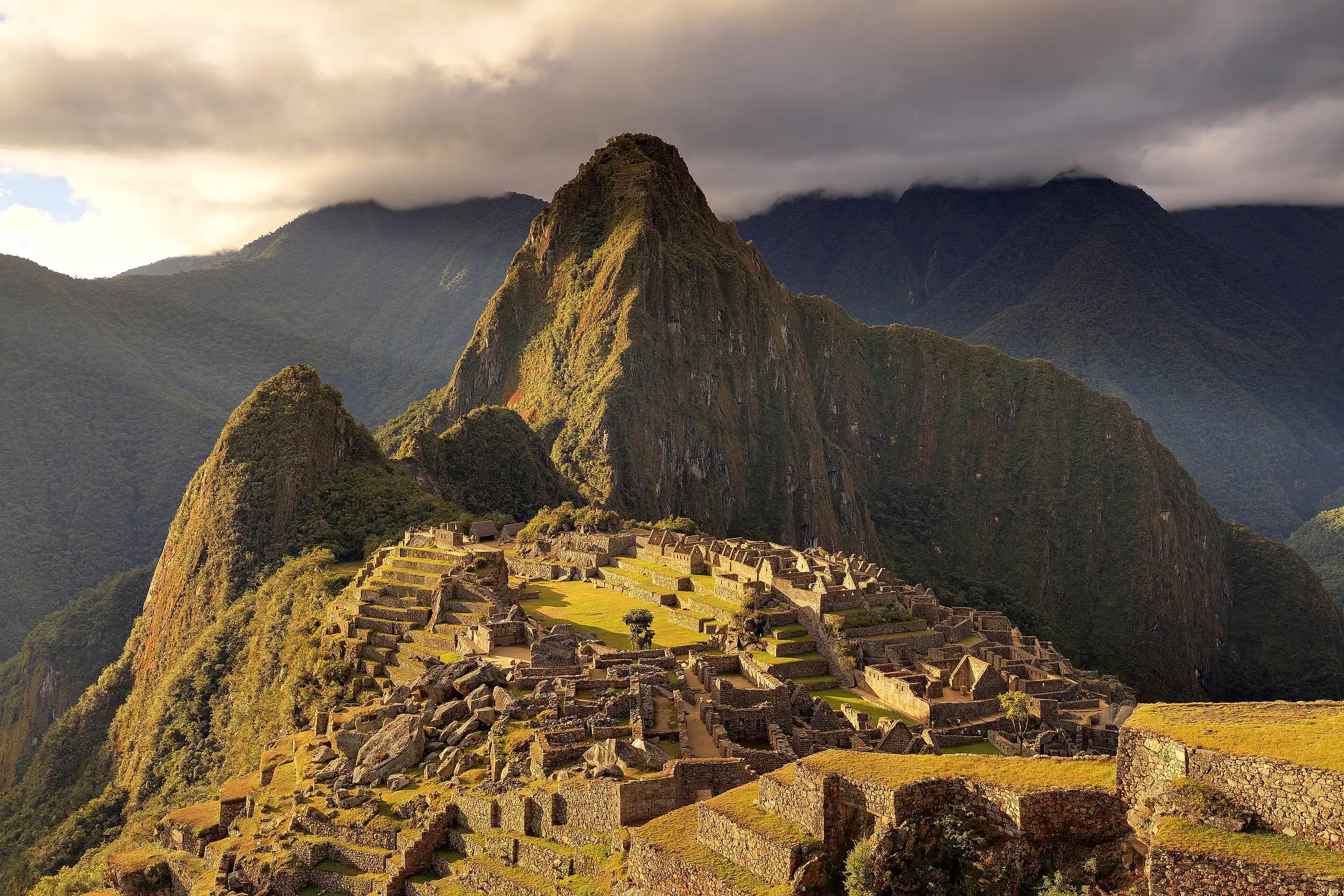 The Machu Picchu citadel and Huayna Picchu in low evening light under dry-season cloud, photographed in late June