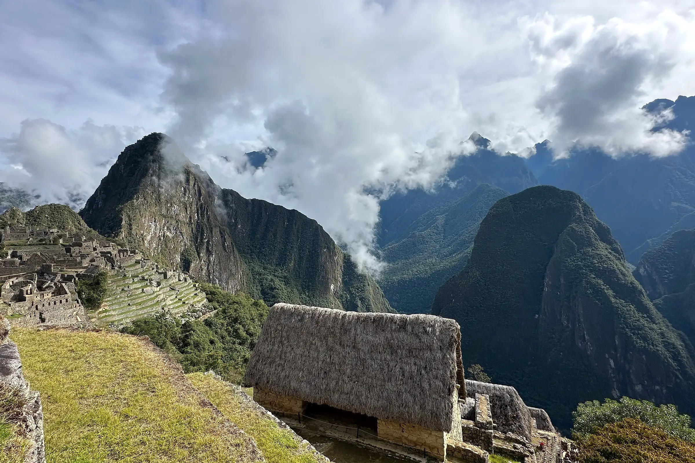 The terraces of Machu Picchu with Huayna Picchu rising behind under breaking cloud