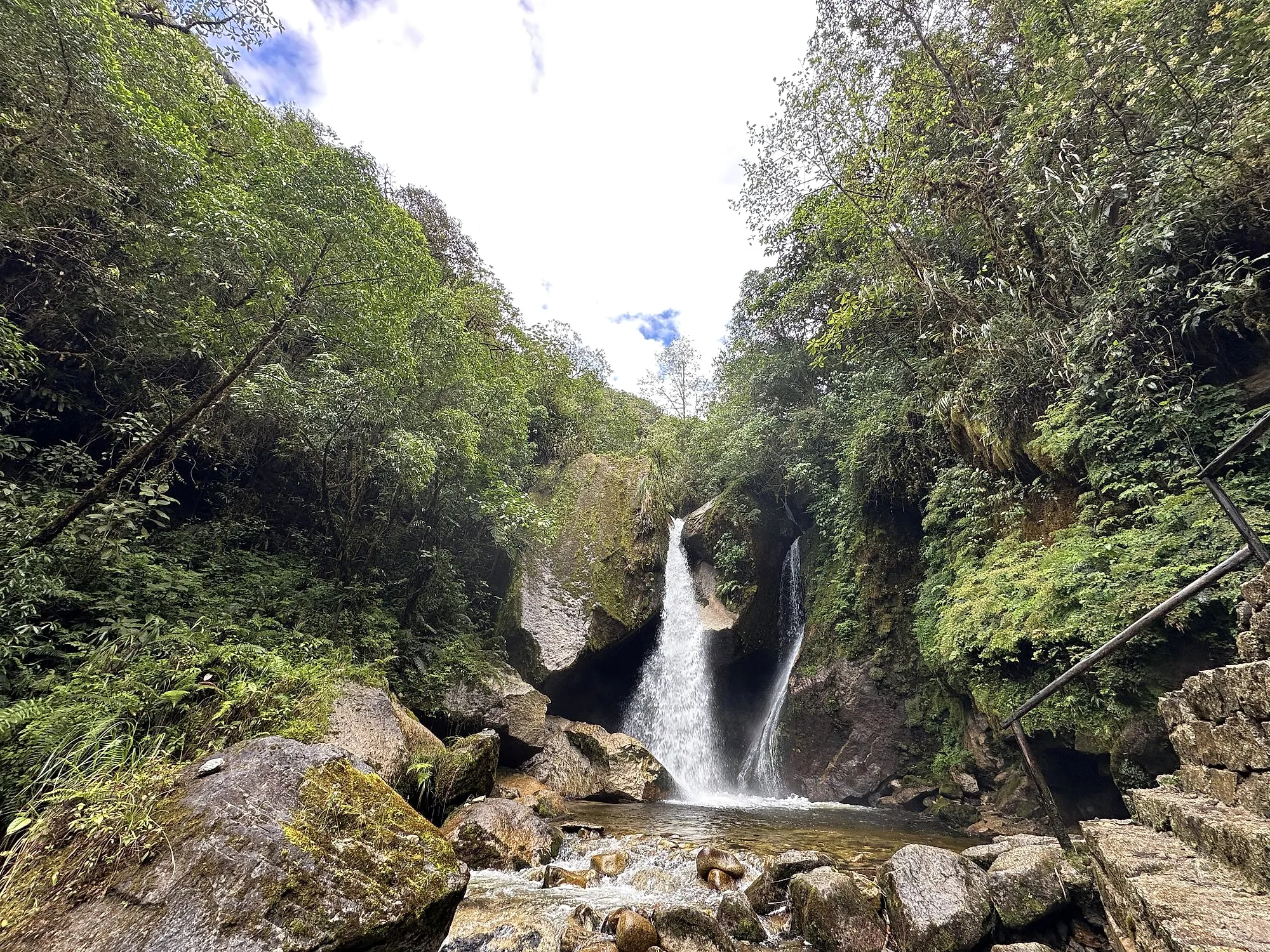 The Mandor waterfall dropping between mossy boulders into a pool in the cloud forest near Aguas Calientes