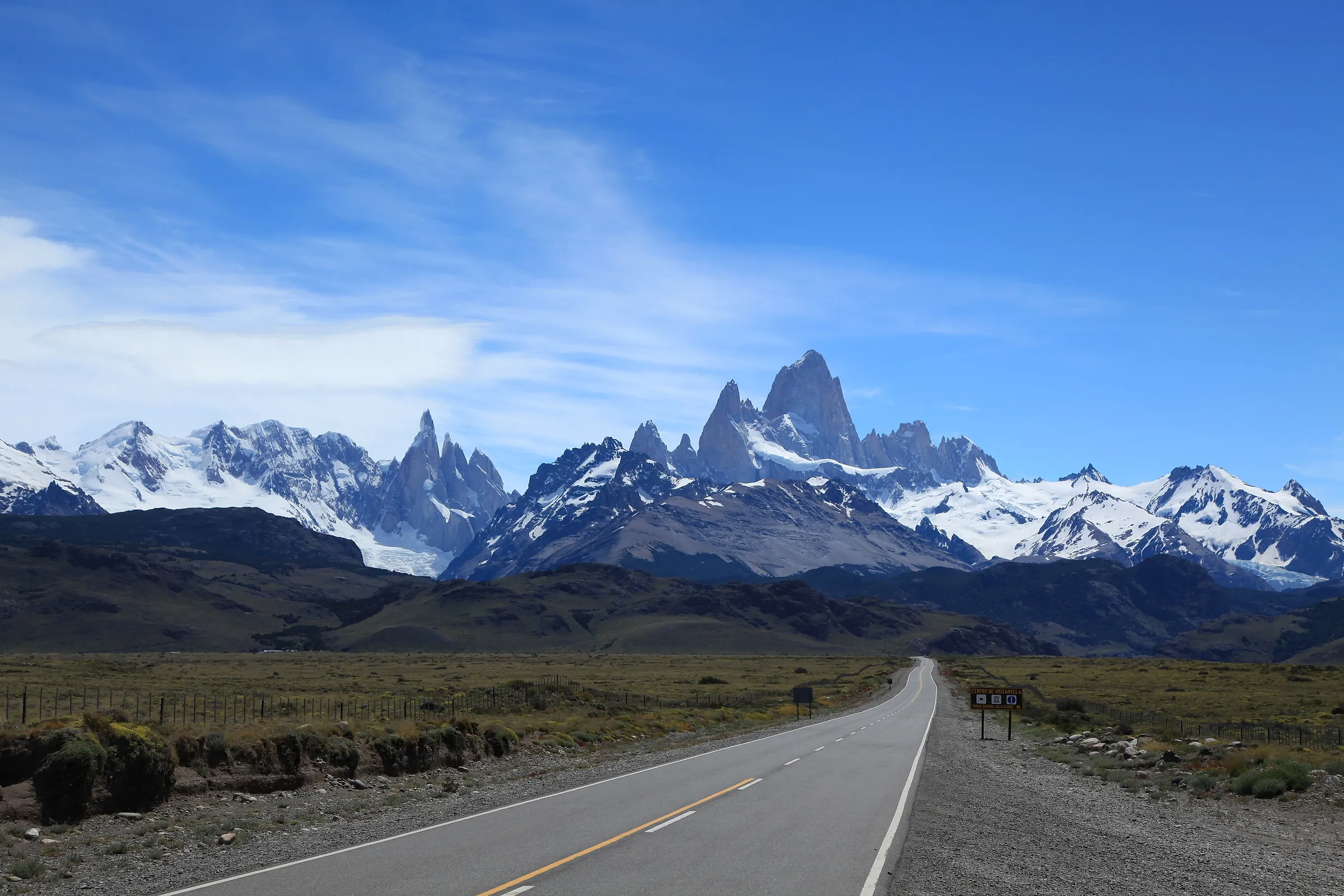 The road to El Chalten running straight across the steppe towards Cerro Torre and Fitz Roy under a blue sky